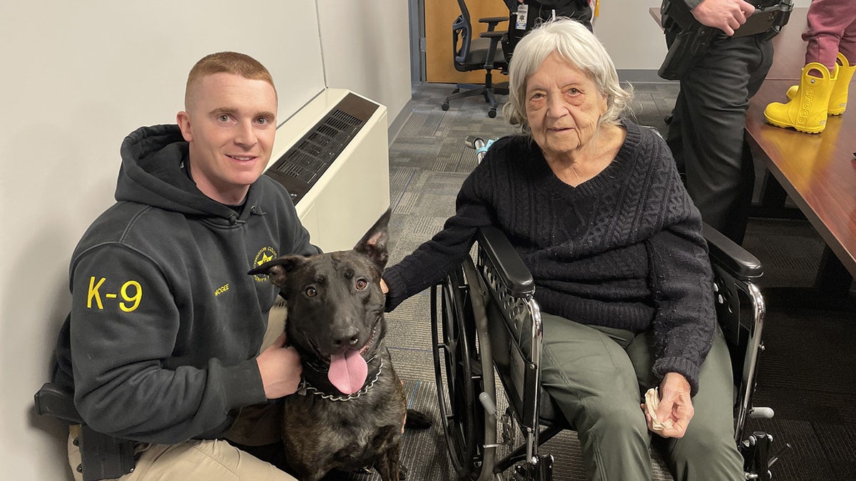 Older woman and sheriff's officer, with K9 dog in front.