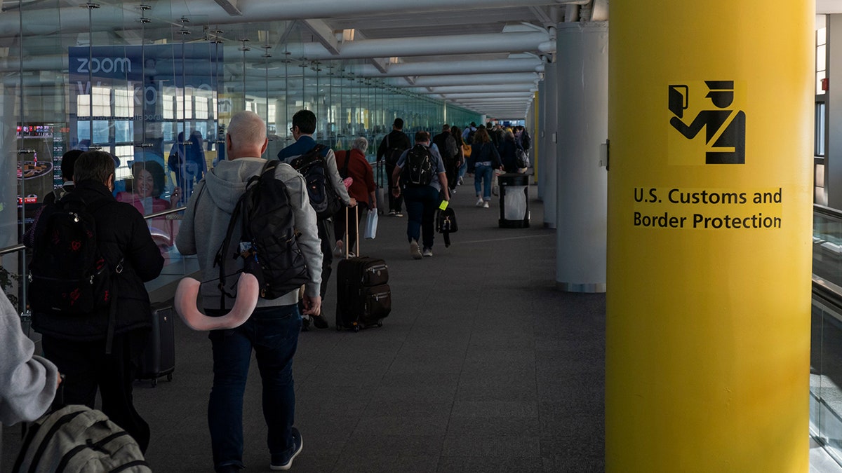 Newark airport passengers walk past CBP sign