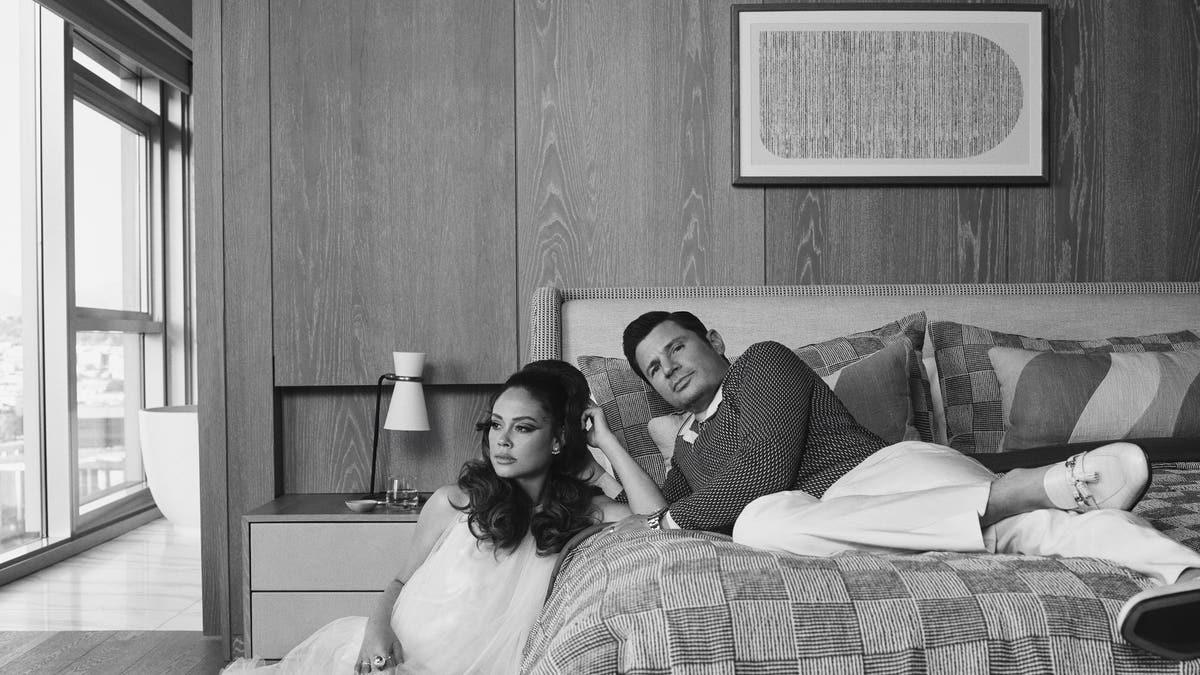 Nick Lachey on a bed with Vanessa Lachey sitting beside the bed