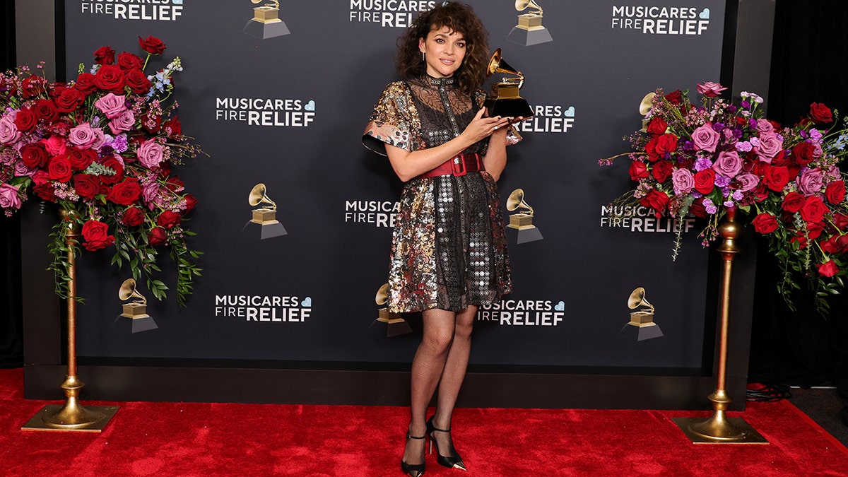 Norah Jones posing with her Grammy Award connected  the reddish  carpet.