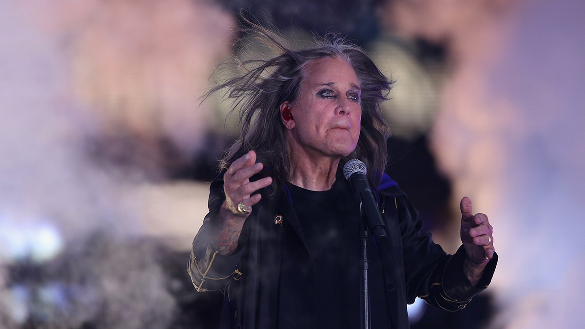 Ozzy Osbourne holding his hands up on stage