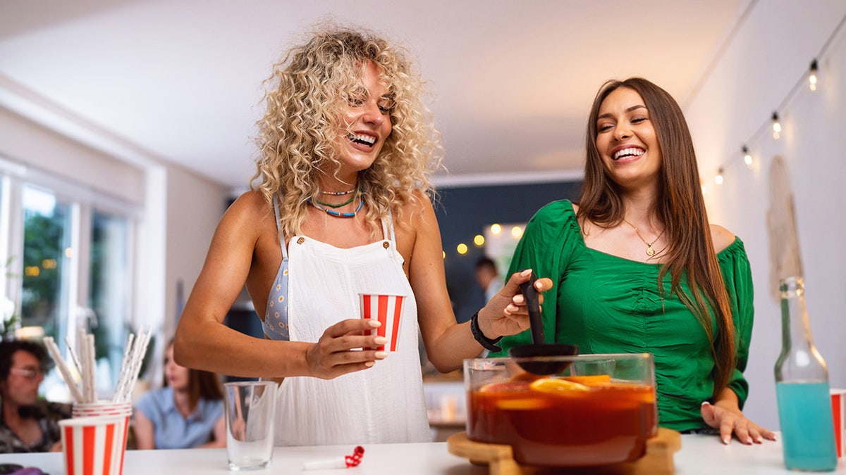 Two women around a bowl at a party.