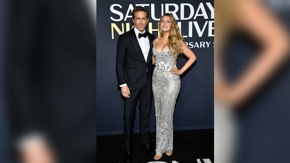 Ryan Reynolds wears a suit next to Blake Lively on red carpet.