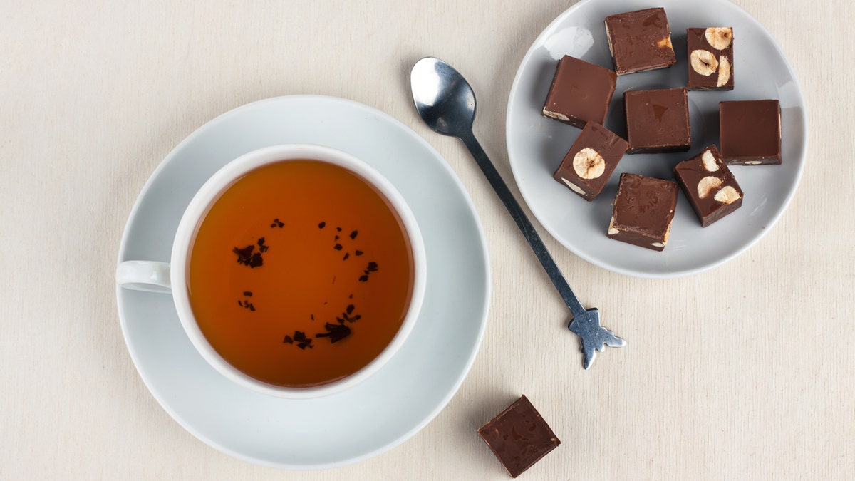 A bird's eye view showing a cup of tea, a stirring spoon and a plate of chocolates.