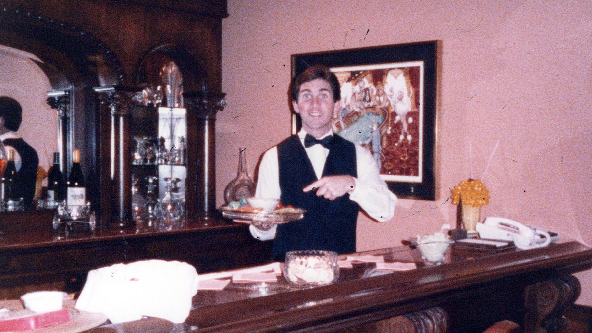 Terry Moogan detrás de una barra sosteniendo un plato.