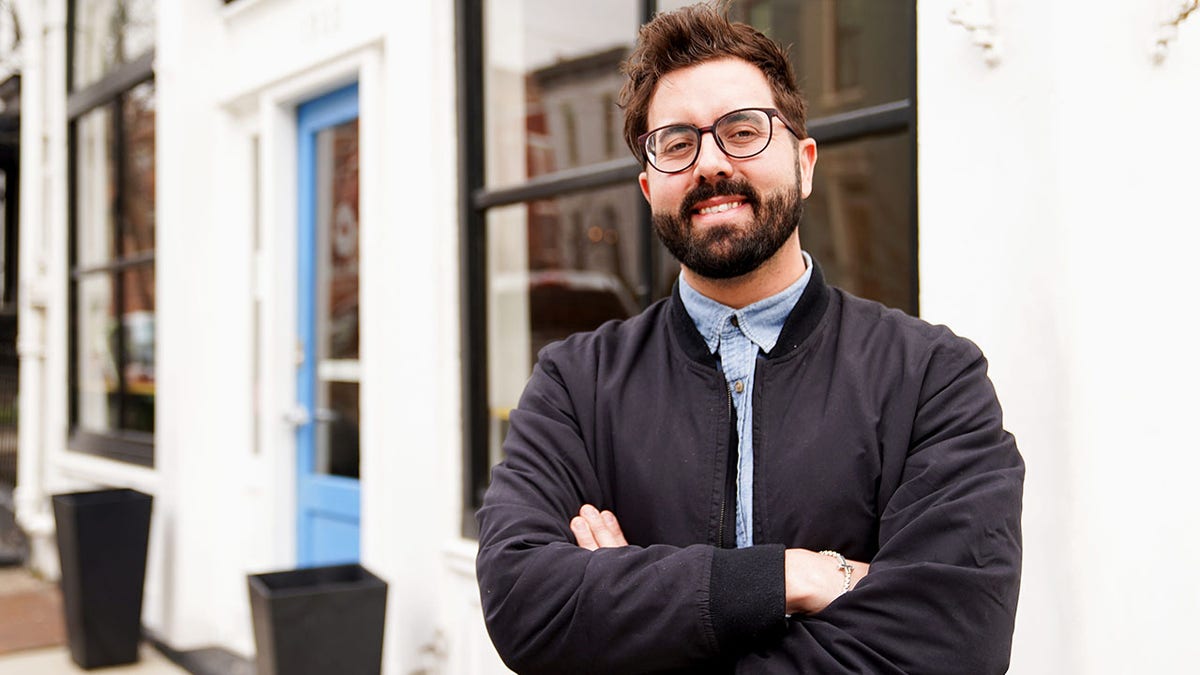 Cory Bowman smiles in front of his coffee shop