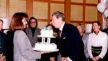 Peggy Grande holds a cake for President Ronald Reagan's 82 birthday in his Century City, California, office after his second term was finished.
