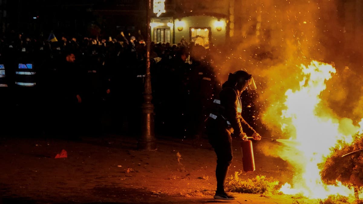 A police officer puts out a fire started by Georgescu supporters