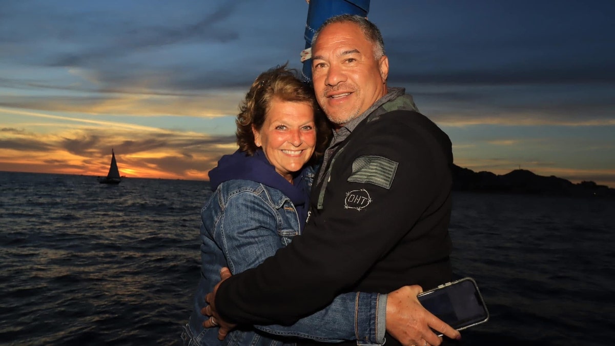 Paul and Christy Akeo posing before a sunset