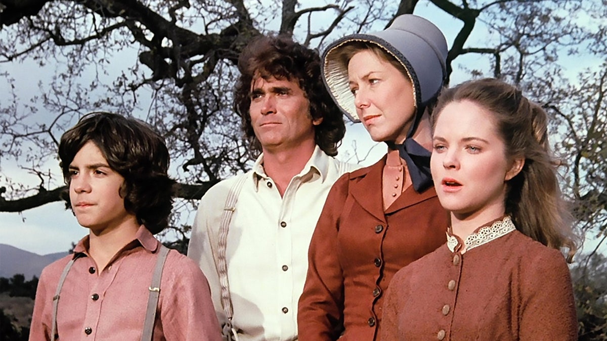 Michael Landon with his castmates in a row in costume filming a scene outdoors.