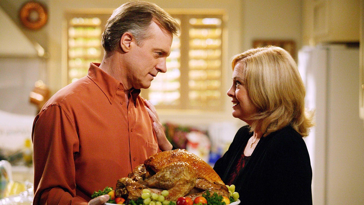 Stephen Collins opposite Catherine Hicks as they act out a scene holding a turkey.