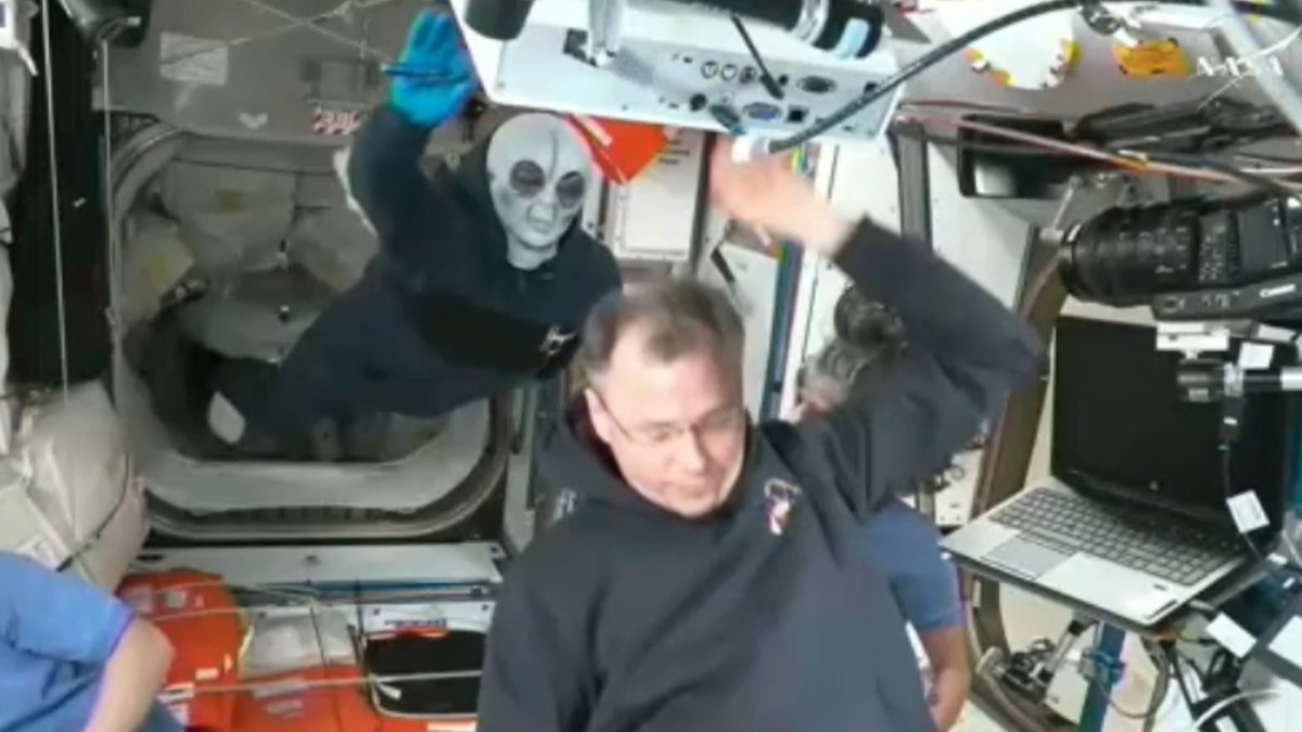 Astronauts wear alien masks to work with crew members