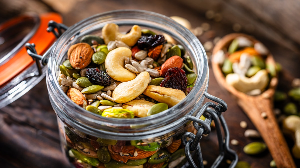 Close up of a glass container filled with organic mix of nuts and seeds.