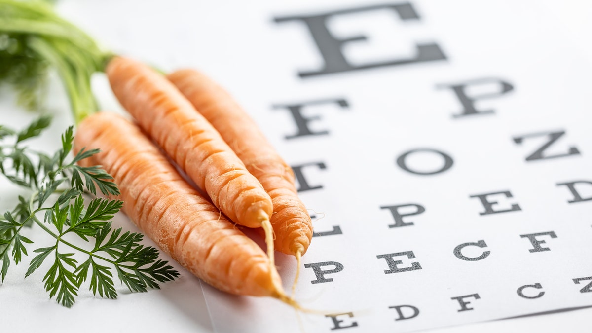 Three carrots rest on an eye chart.