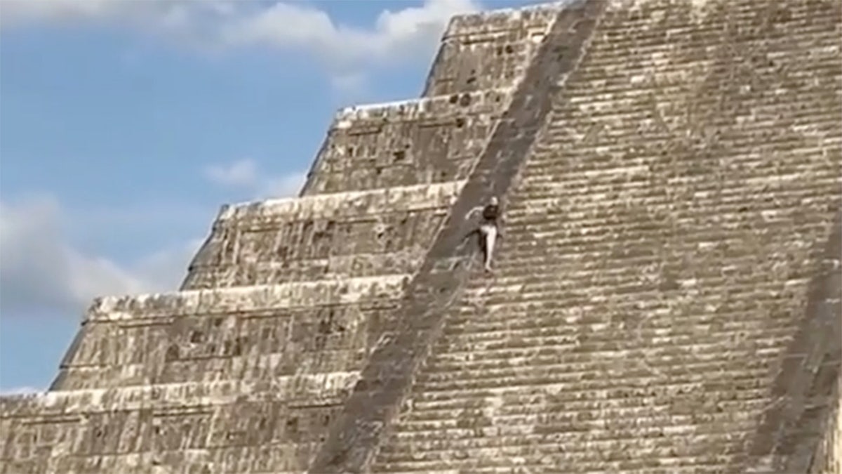 A tourist scale the side of the Kukulcan temple