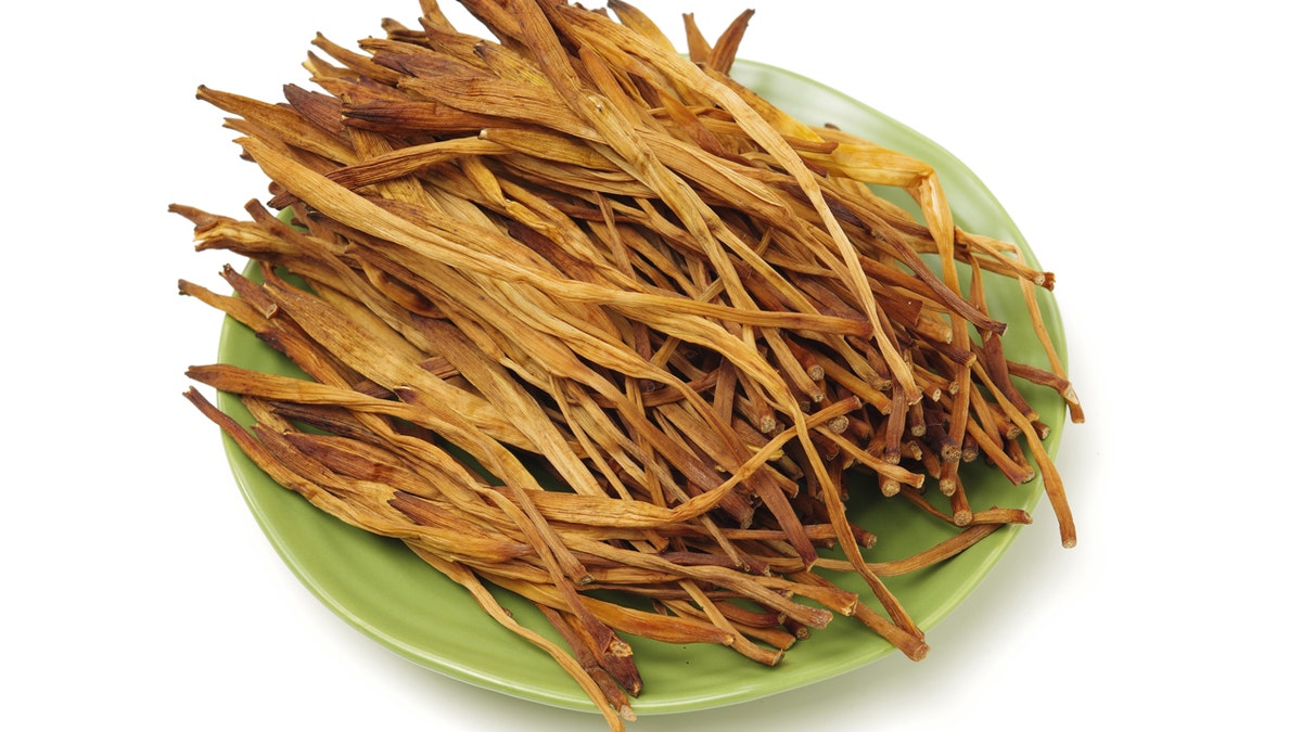 Dried lily flowers are shown on a green plate.