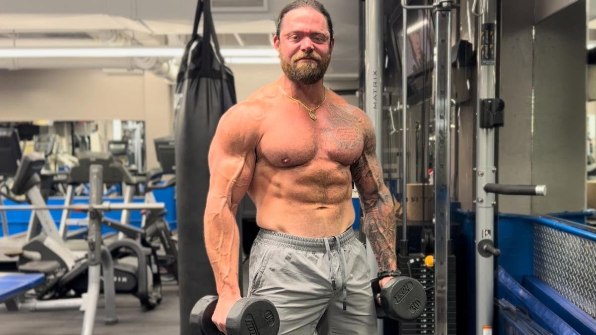 NYPD detective Eddie Barrett flexing his muscles with his top off, working out at a gym.