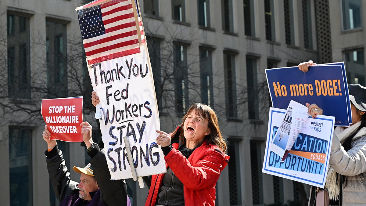 Protesters hold signs in solidarity with federal workers