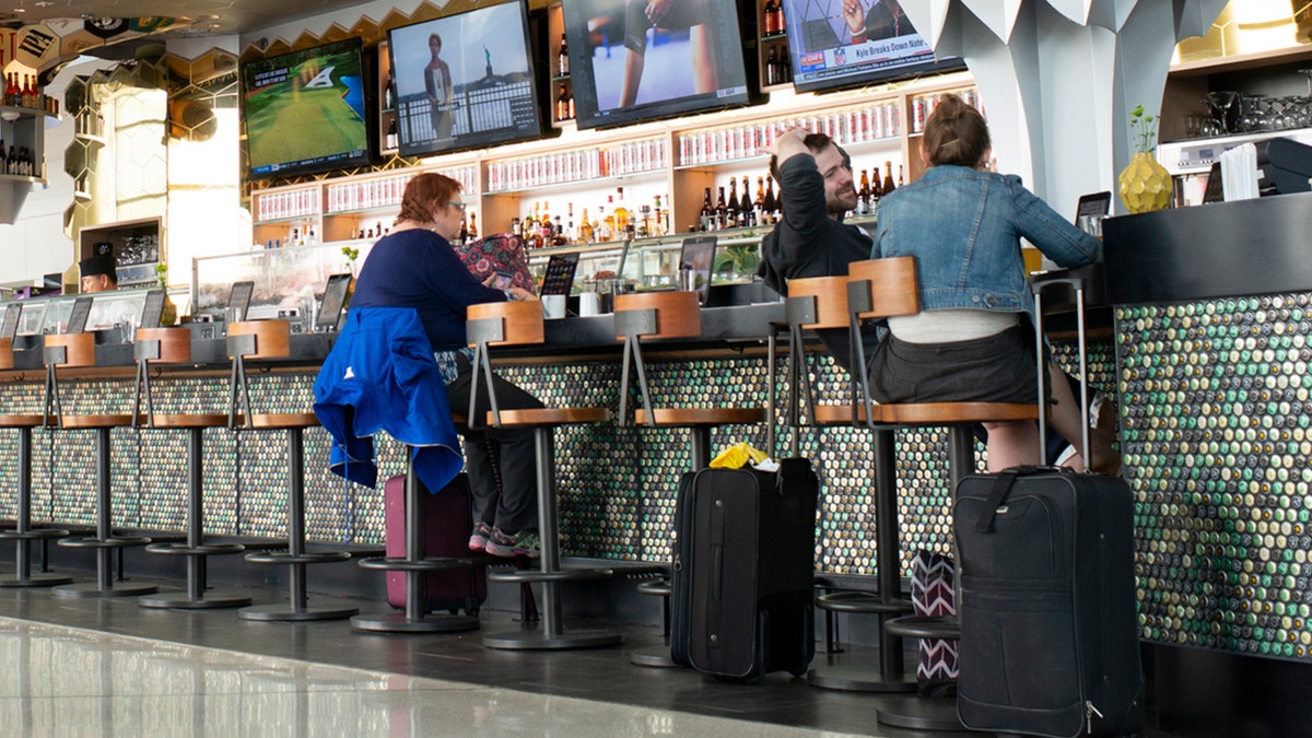 Airline passengers enjoy drinks at an airport bar.