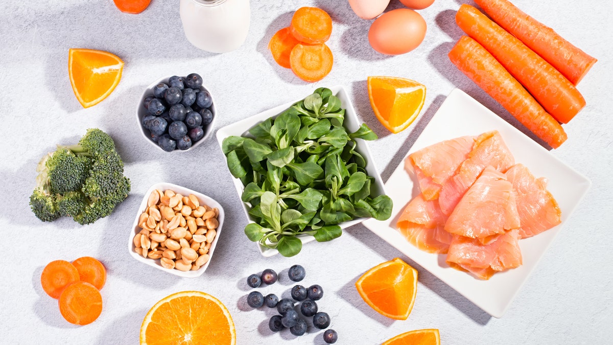 An assortment of foods for good vision, including broccoli, blueberries, nuts, fatty fish, oranges and carrots.