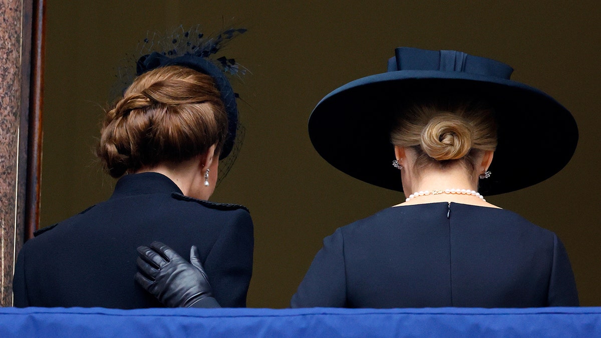 Kate Middleton and Sophie with their backs turned as Sophie puts her hand on Kate's back.