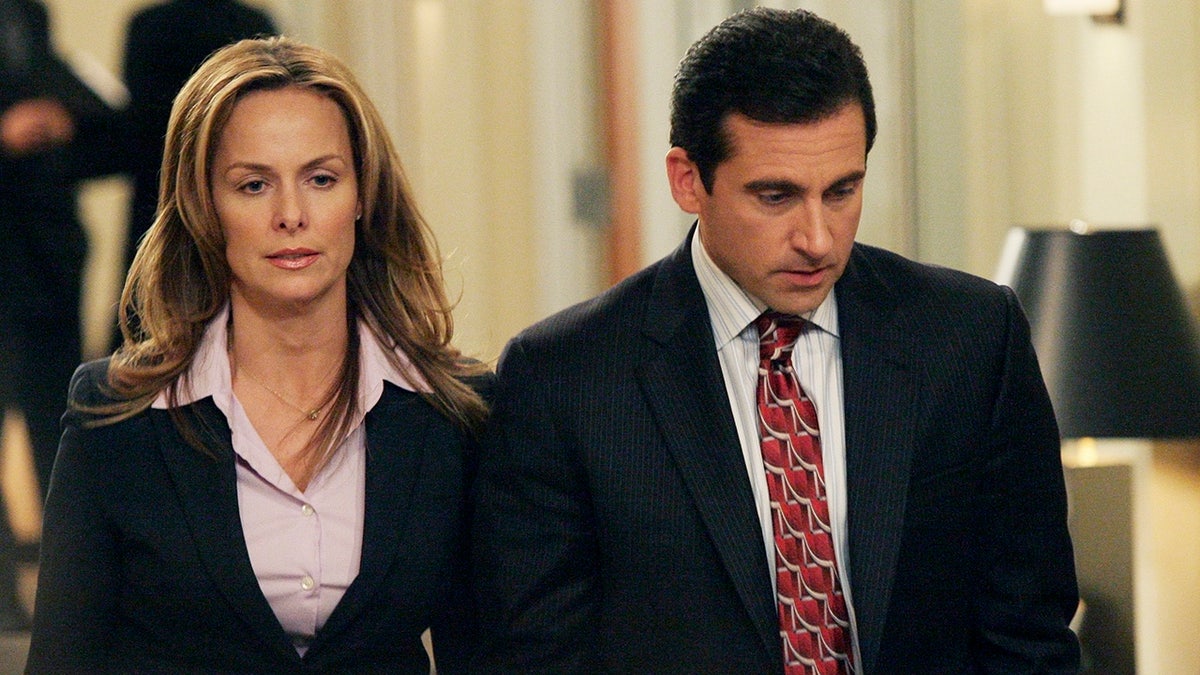 Melora Hardin in a suit walking alongside Steve Carell in "The Office."