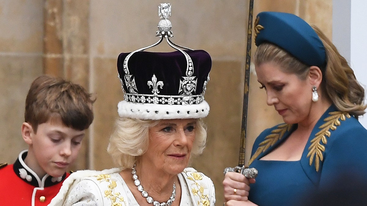 Queen Camilla wearing a white and gold dress with a crown.