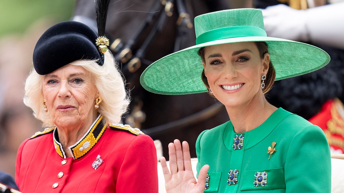 Kate Middleton in a green dress with a matching hat sitting next to Queen Camilla on a royal carriage.