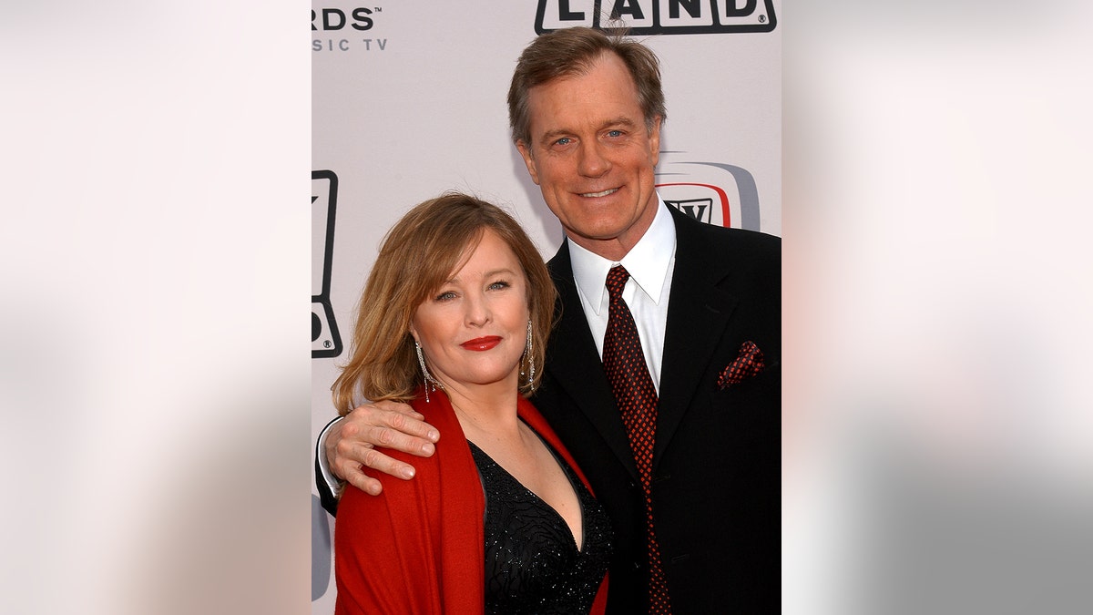 Stephen Collins in a black blazer with his arm around his then-wife wearing a red blazer and a black dress.