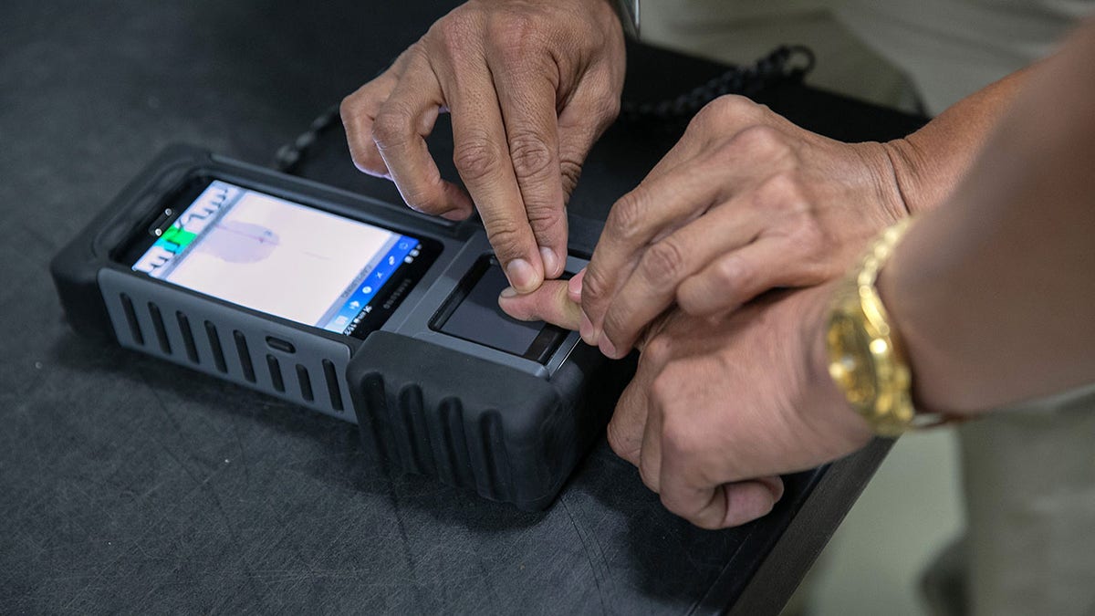 This file image shows a Guatemalan immigration agent fingerprinting a traveler during a secondary screening while being instructed by a U.S. Department of Homeland Security advisor on Aug. 26, 2019 in Guatemala City.