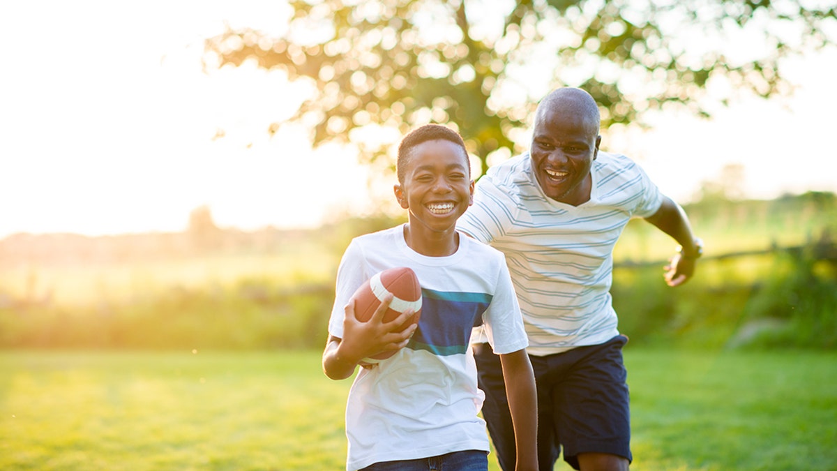 Father and son playing football outside