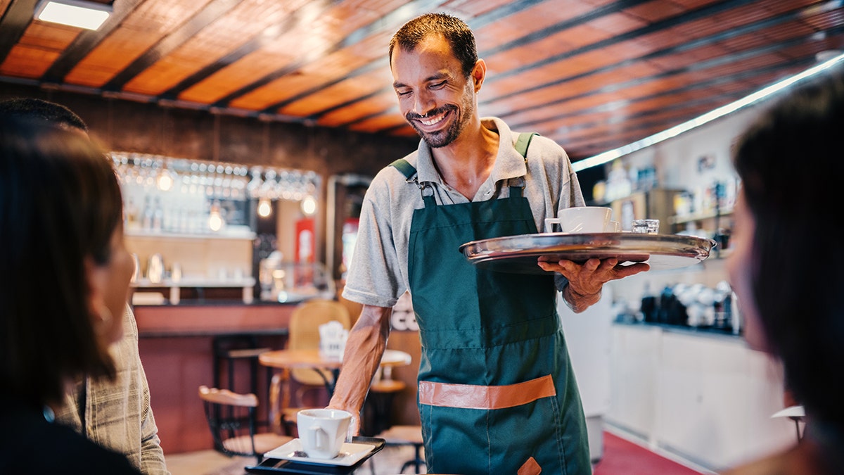 The waiter delivers coffee to the table