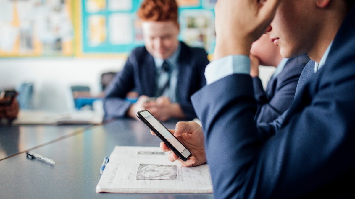 Student on his phone in a classroom