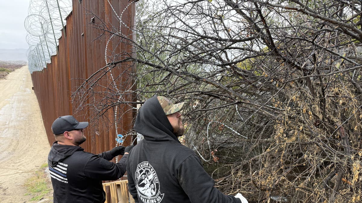 volunteers putting up razor wire at hold in border fence