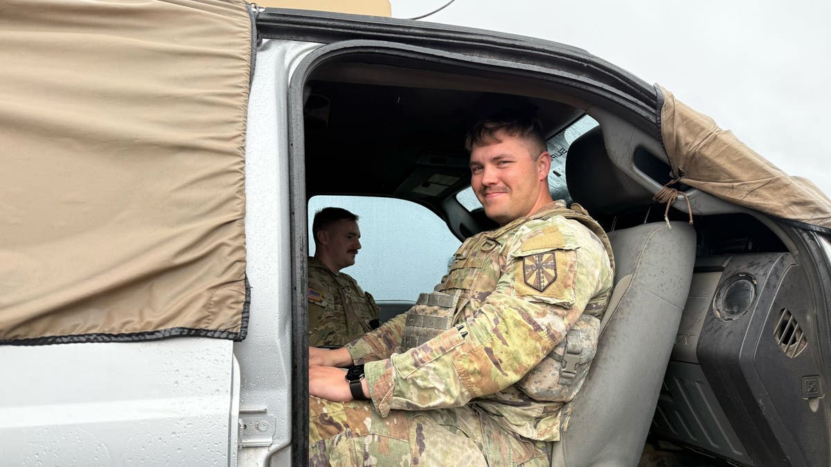 Army soldier in seat of vehicle smiling