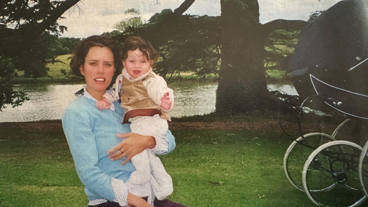 Ione Skye holding her baby daughter wearing a light blue sweater outdoors.