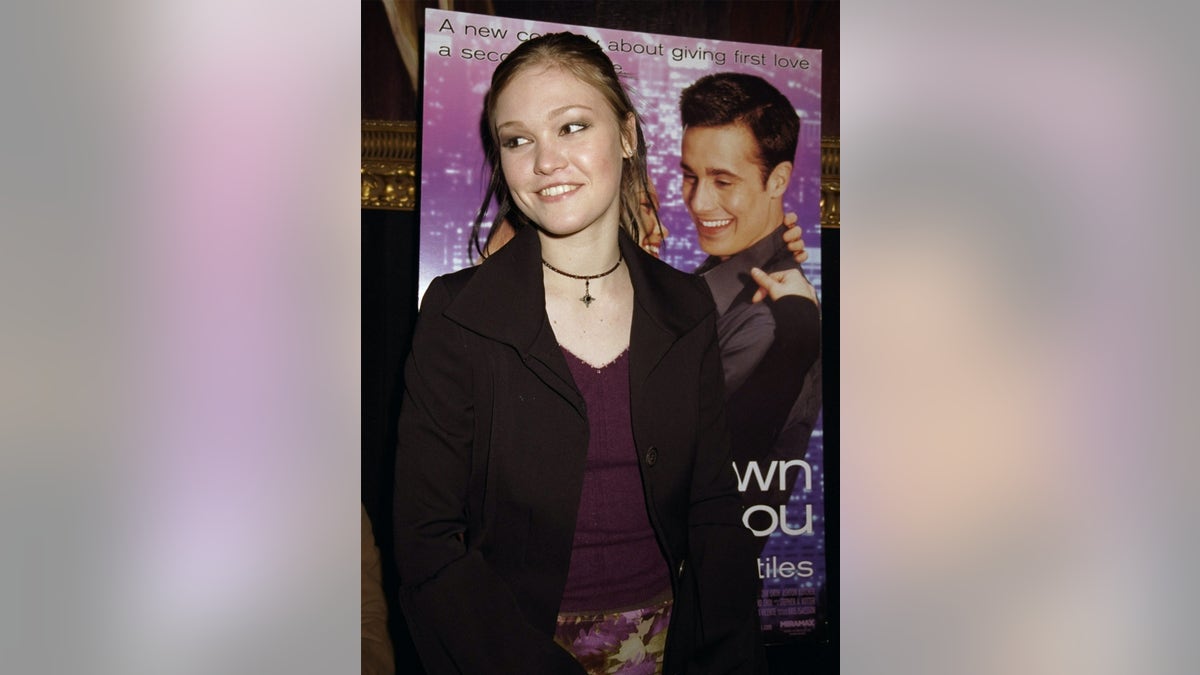 Julia Stiles posing in front of the "To you" poster