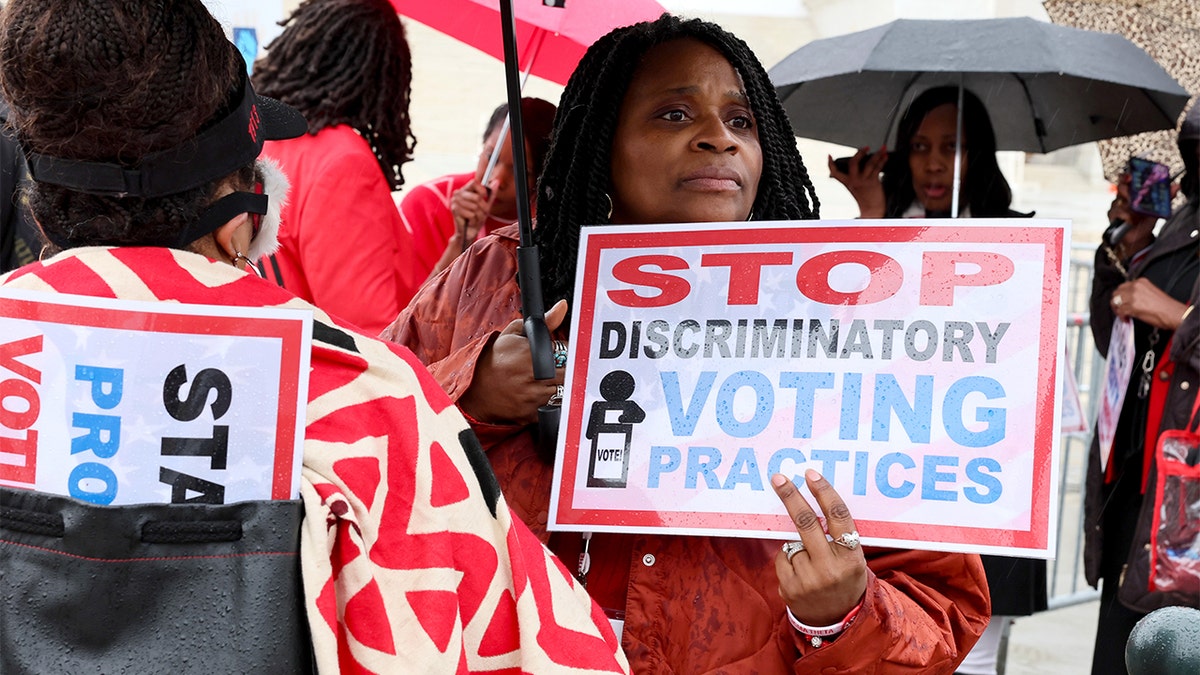 Protesters hold signs saying "Stop Discriminatory Voting"