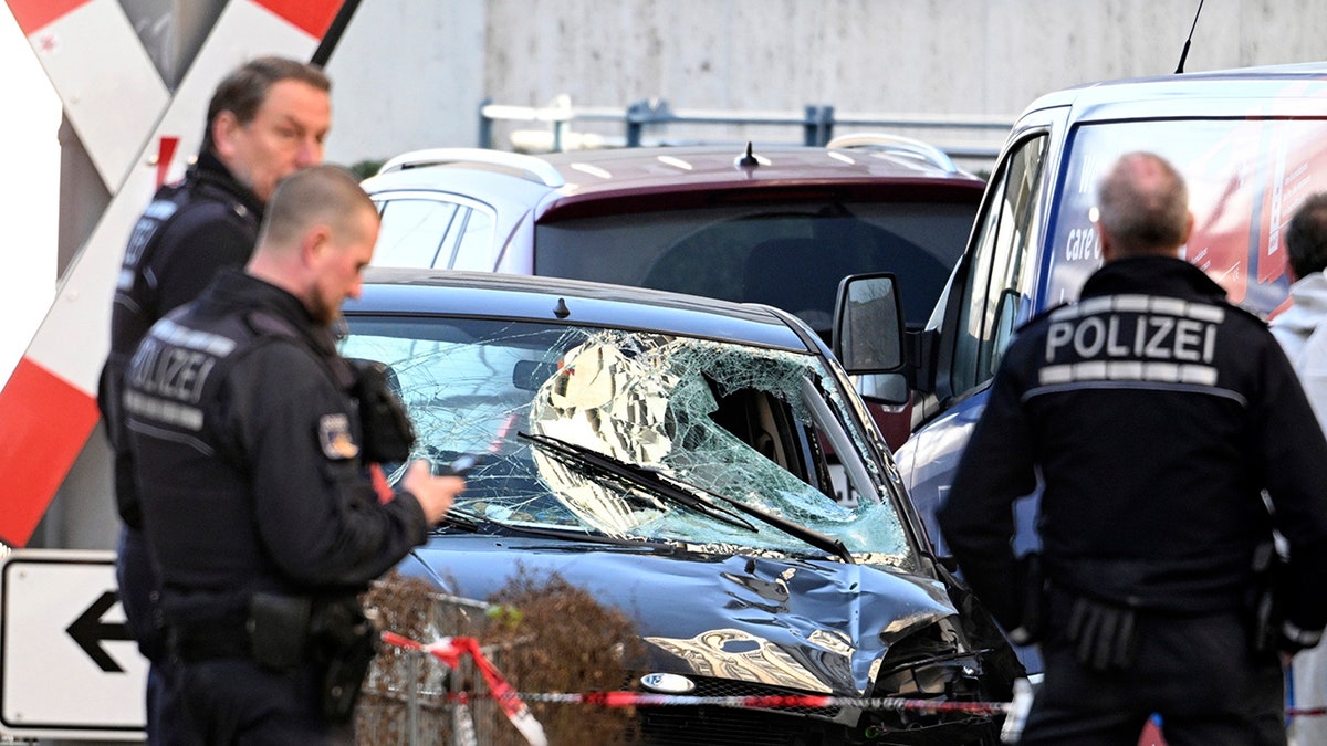 there are two police officers standing next to a car that has been smashed