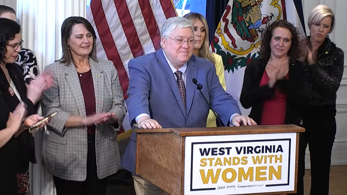 The village. Patrick Morissi, Riley Gens, IWF's Heather Higins (R.), and Sen Patricia Rukar, R-Charlas Town, (L.) are seen in a bill-singing event.