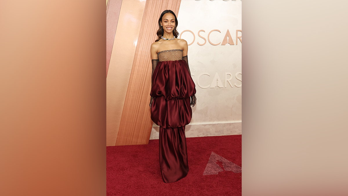 Saldana usava um vestido vermelho em camadas no tapete vermelho do Oscar de 2025.