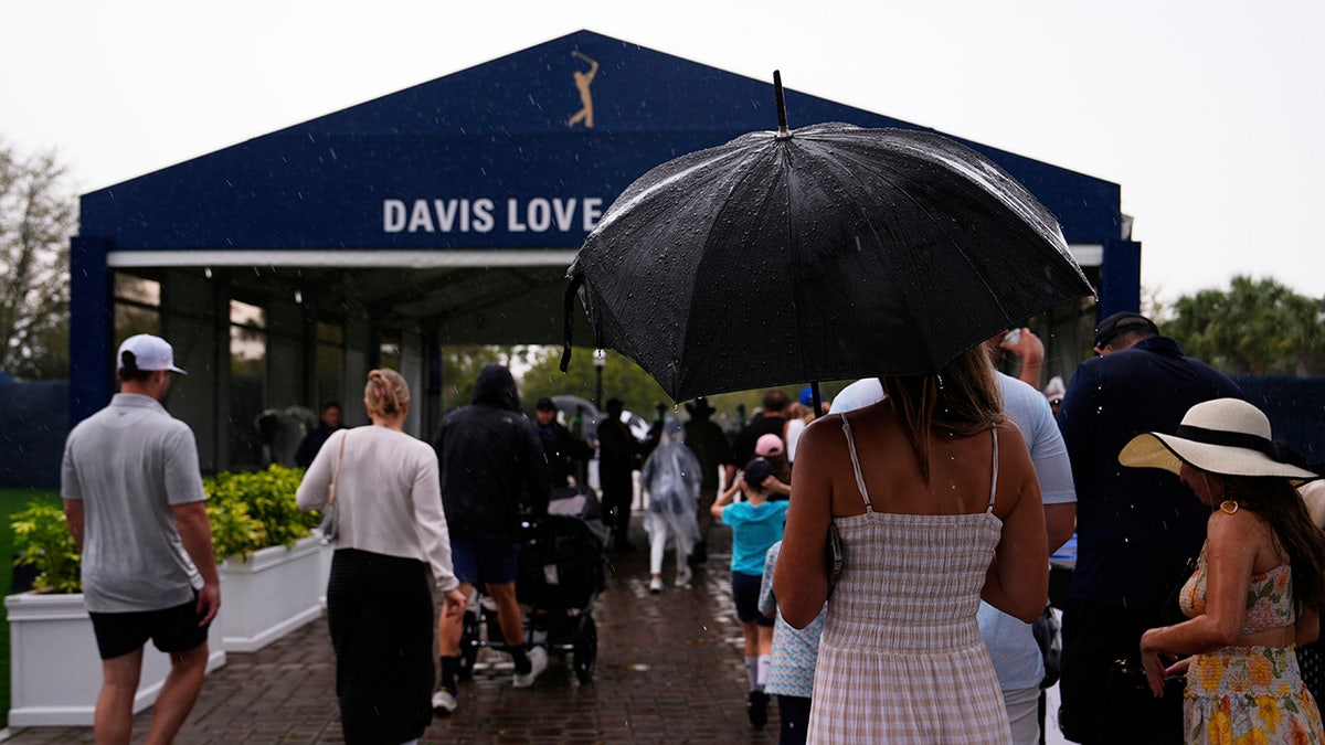 Golf fans walk in rain