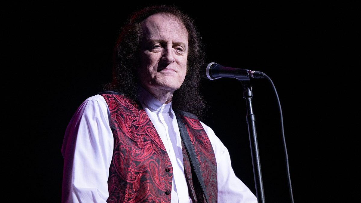 Tommy James standing at microphone