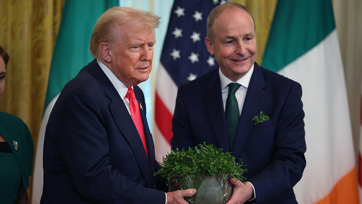 Taoiseach Irish Micheál Martin, on the right, introduces President Donald Trump a clover bow