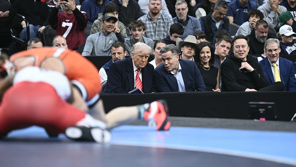 US President Donald Trump speaks with Senator Dave McCormick sitting next to Tesla and SPaceX CEO Elon Musk and US Representative Jim Jordan (R-OH) as they watch the men's NCAA wrestling competition at the Wells Fargo Center in Philadelphia, Pennsylvania, on March 22, 2025. (Photo by Brendan SMIALOWSKI / AFP) (Photo by BRENDAN SMIALOWSKI/AFP via Getty Images)