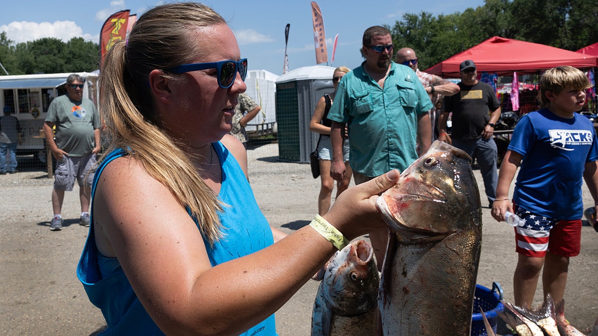 A woman holds two dead invading carp during a game in Illinois.