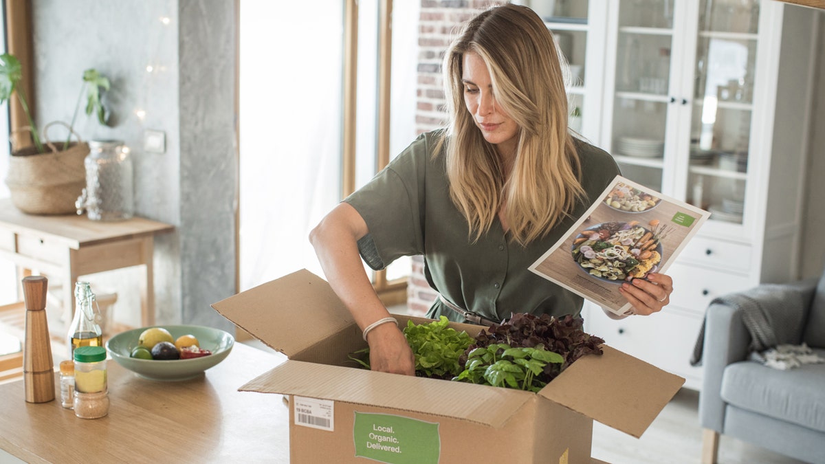 A woman looks through a box of organic food that was delivered.