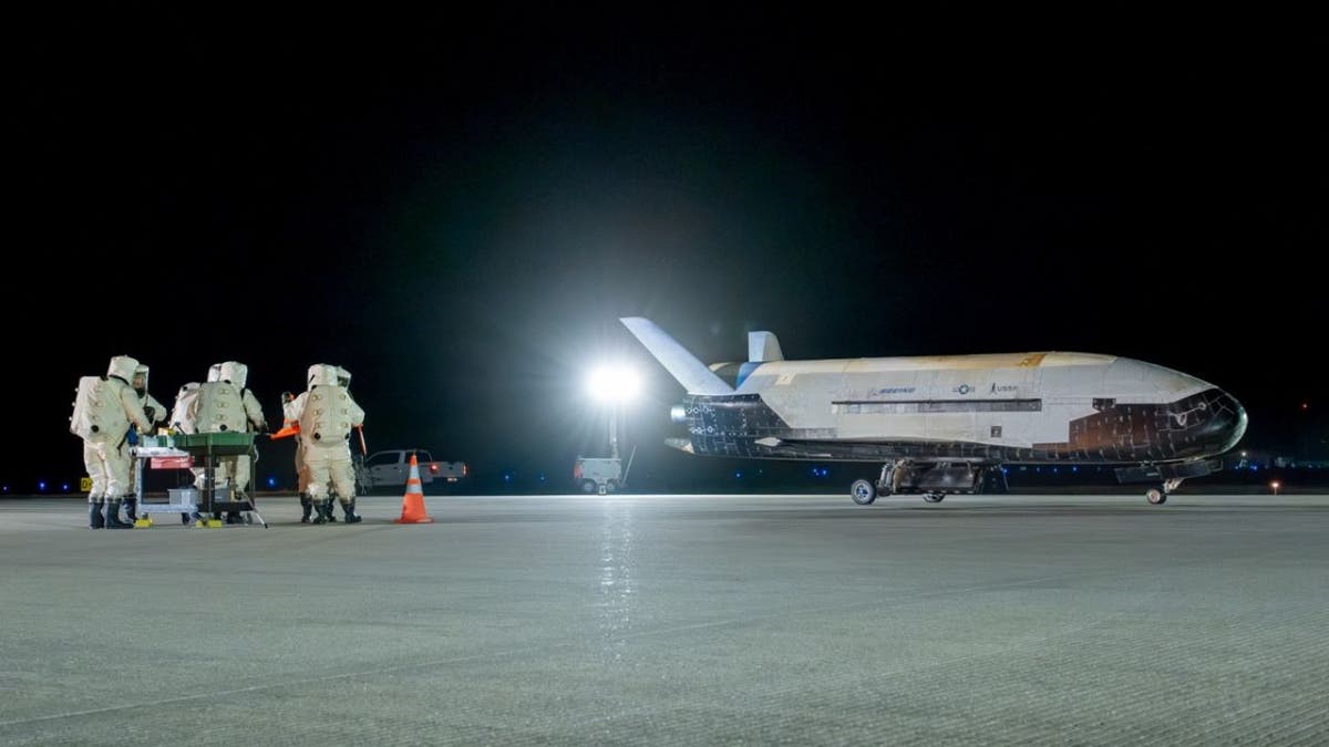 Workers walk to the United States Space Force’s secretive X-37B space plane