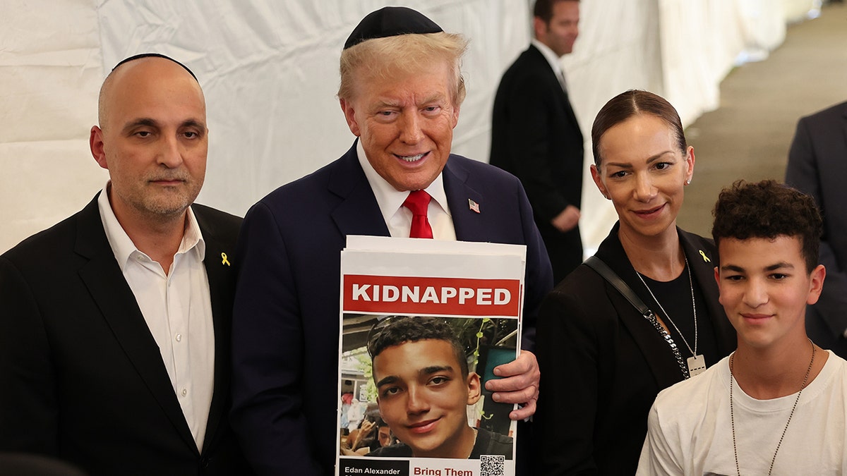 Donald Trump holds a photo of Edan Alexander