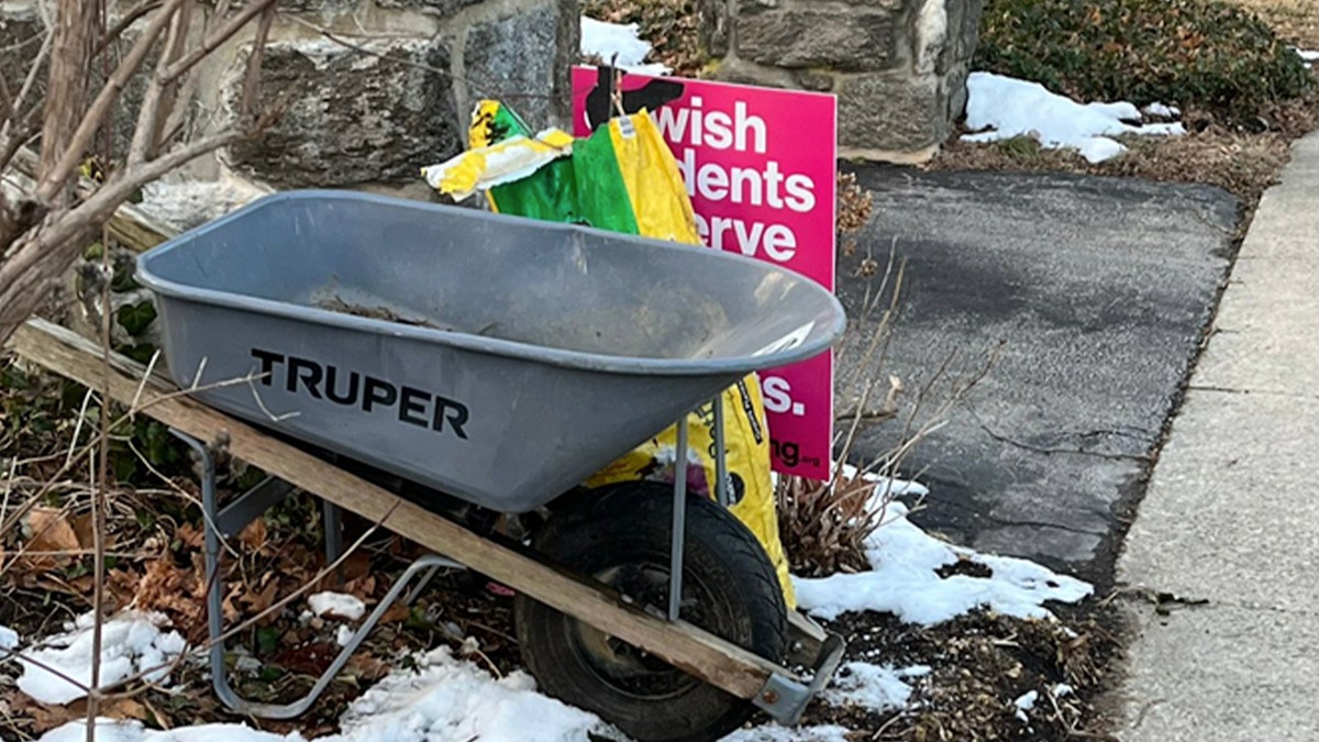 School board member blocks sign using a wheelbarrow and dirt